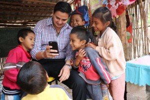El delegado del Conafe en Yucatán, Carlos Carrillo Paredes, muestra su celular a los pequeños educandos que visitó