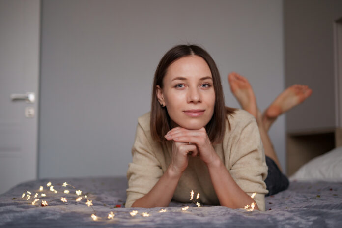 Lovely woman lying on bed with glowing lights